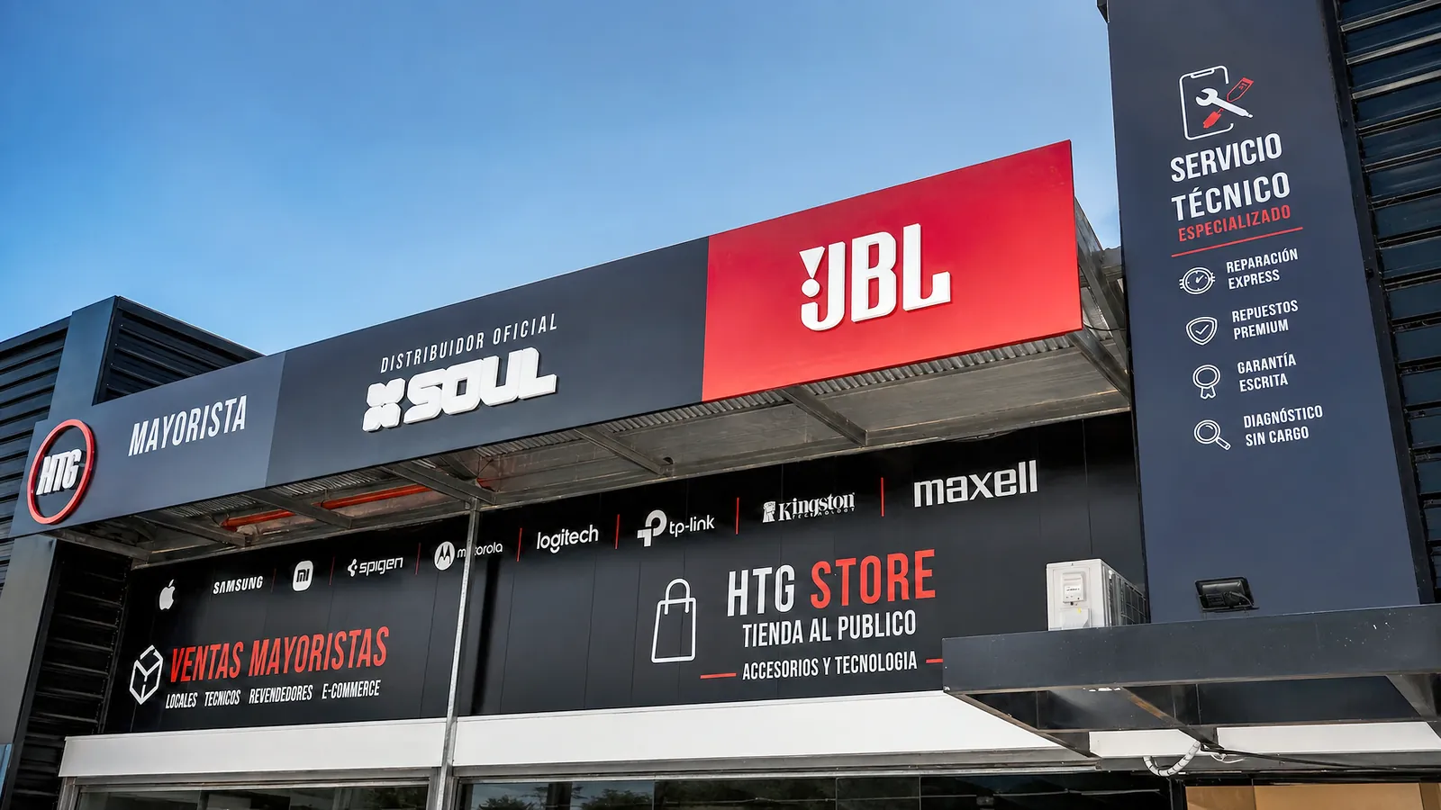 Fachada de HTG en Pilar: los carteles de HTG Mayorista, distribuidor oficial SOUL, JBL, servicio tecnico especializado, ventas mayoristas para locales, tecnicos, revendedores y e-commerce, y HTG Store